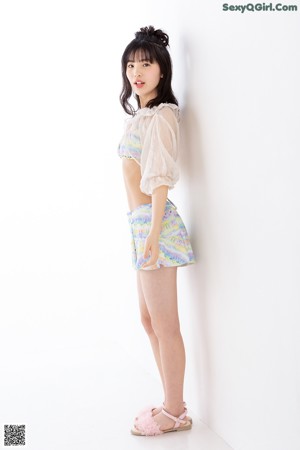 A young woman in a white top and colorful shorts.