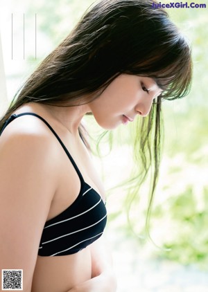 A woman in a black and white striped bikini sitting on a chair.