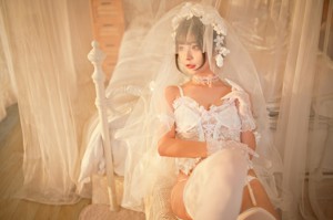 A woman in a white lingerie sitting on a bed.