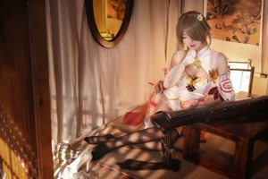 A woman sitting on a bed holding a fan.