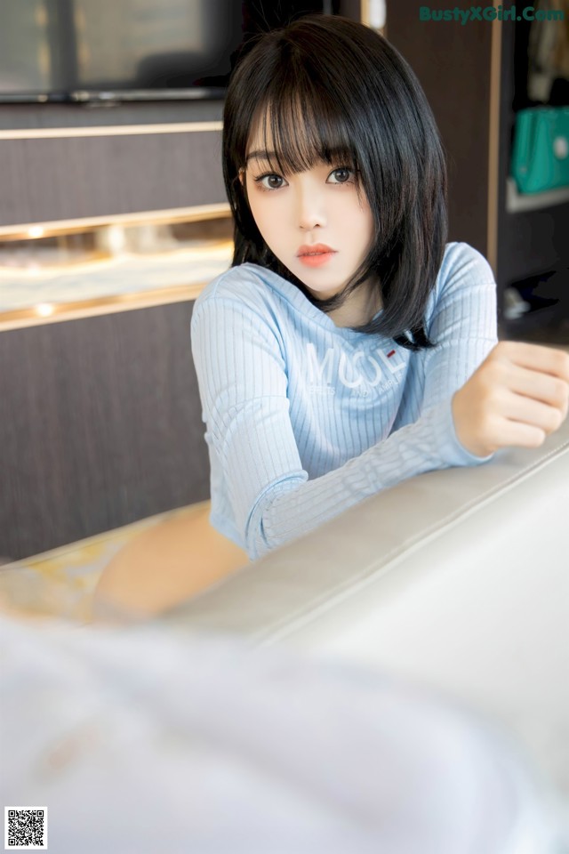 A woman sitting on top of a bed next to a television.