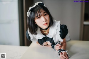 A woman in a maid outfit sitting on a kitchen counter.