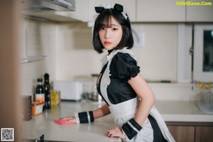 A woman in a maid outfit cleaning the floor.