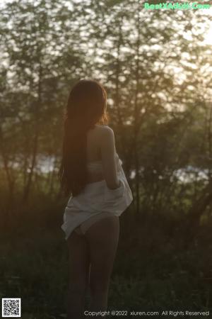 A woman in a white dress standing in a stream.