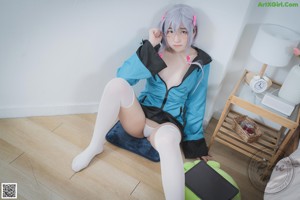 A woman in a blue jacket holding a green stuffed animal.