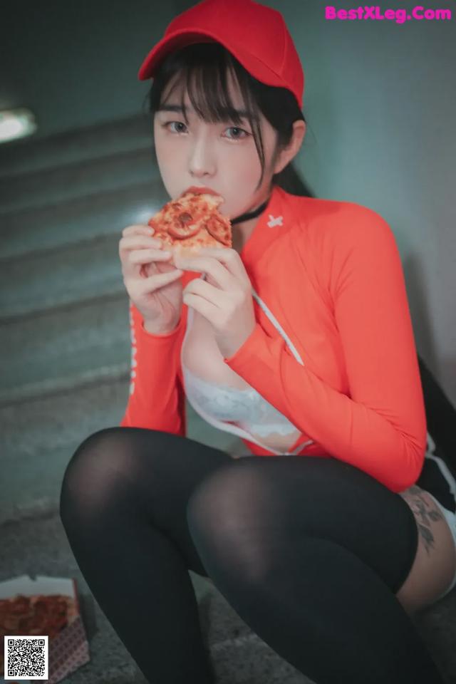 A woman sitting on the stairs eating a slice of pizza.