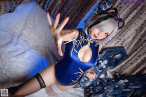 A woman in a blue bodysuit laying on a white fur rug.