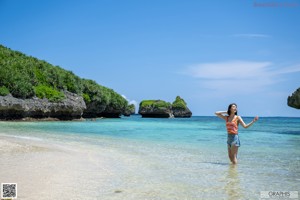 A woman in a bikini sitting in the water.