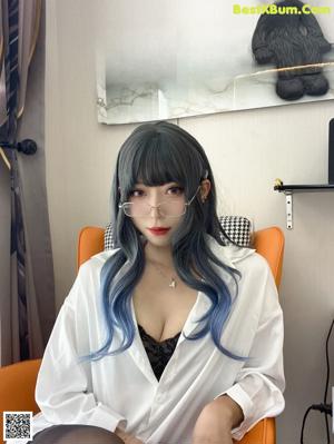 A woman with blue hair sitting on a chair.