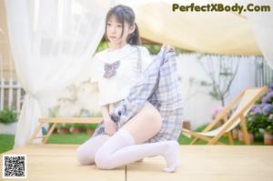 A woman in a white shirt and white stockings is posing for the camera.