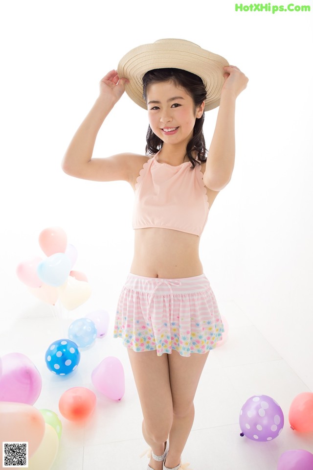 A woman in a pink bikini top and a straw hat posing for a picture.