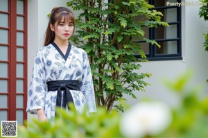 A woman in a blue and white floral dress posing by a pool.