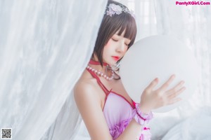 A woman in a pink lingerie sitting on a bed.