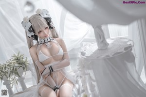 A woman in a white lingerie sitting on a bed.