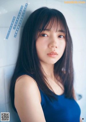 A young woman sitting on a chair wearing a blue cardigan.
