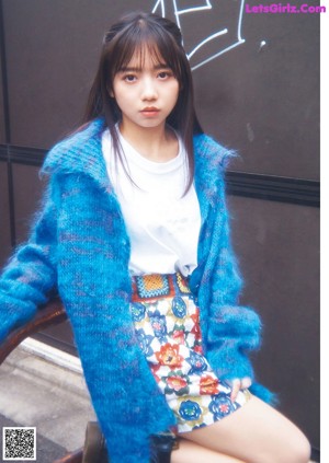 A woman in a blue sweater is posing for a magazine.