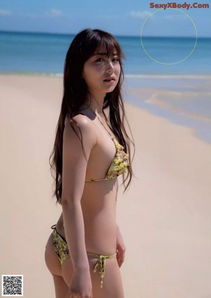 A woman in a wet suit holding a surfboard on the beach.