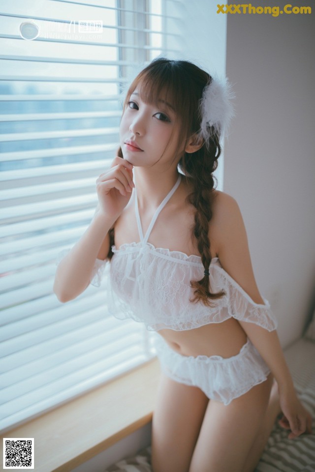 A woman in a white lingerie sitting on a window sill.