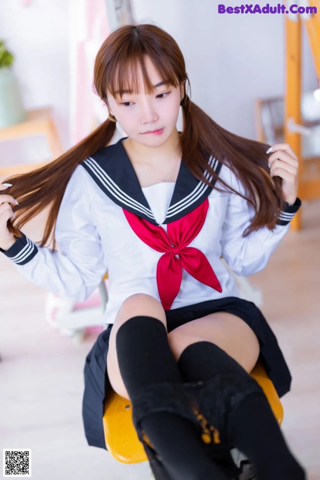 A woman in a school uniform sitting on a chair.