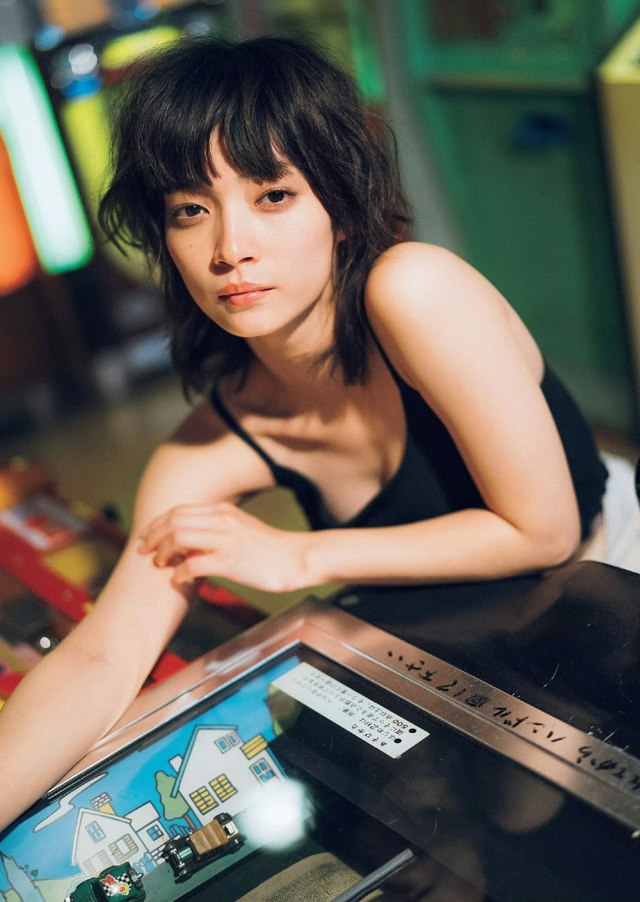 A woman sitting at a table with a pinball machine.