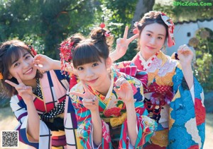 A group of three women in colorful kimonos sitting on steps.