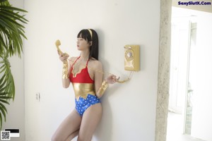 A woman in a bathing suit standing next to a palm tree.