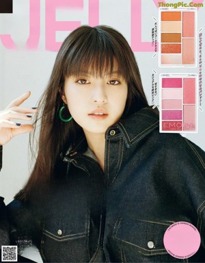 A woman sitting on the floor wearing a denim jacket and jeans.