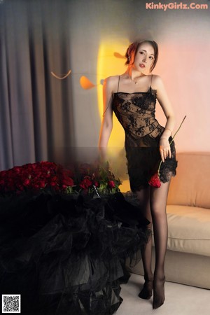 A woman in a black dress holding a gun.